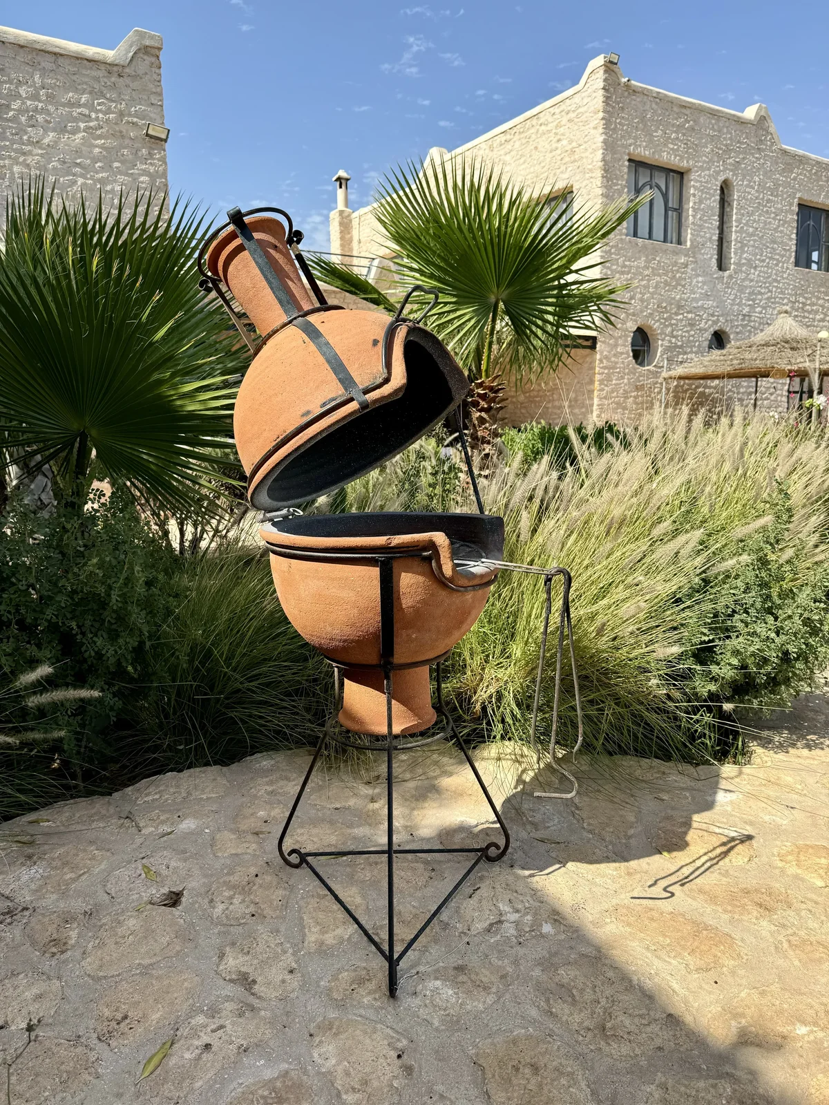 Barbecue en terre cuite dans le jardin de la villa entouré de végétation et de palmiers