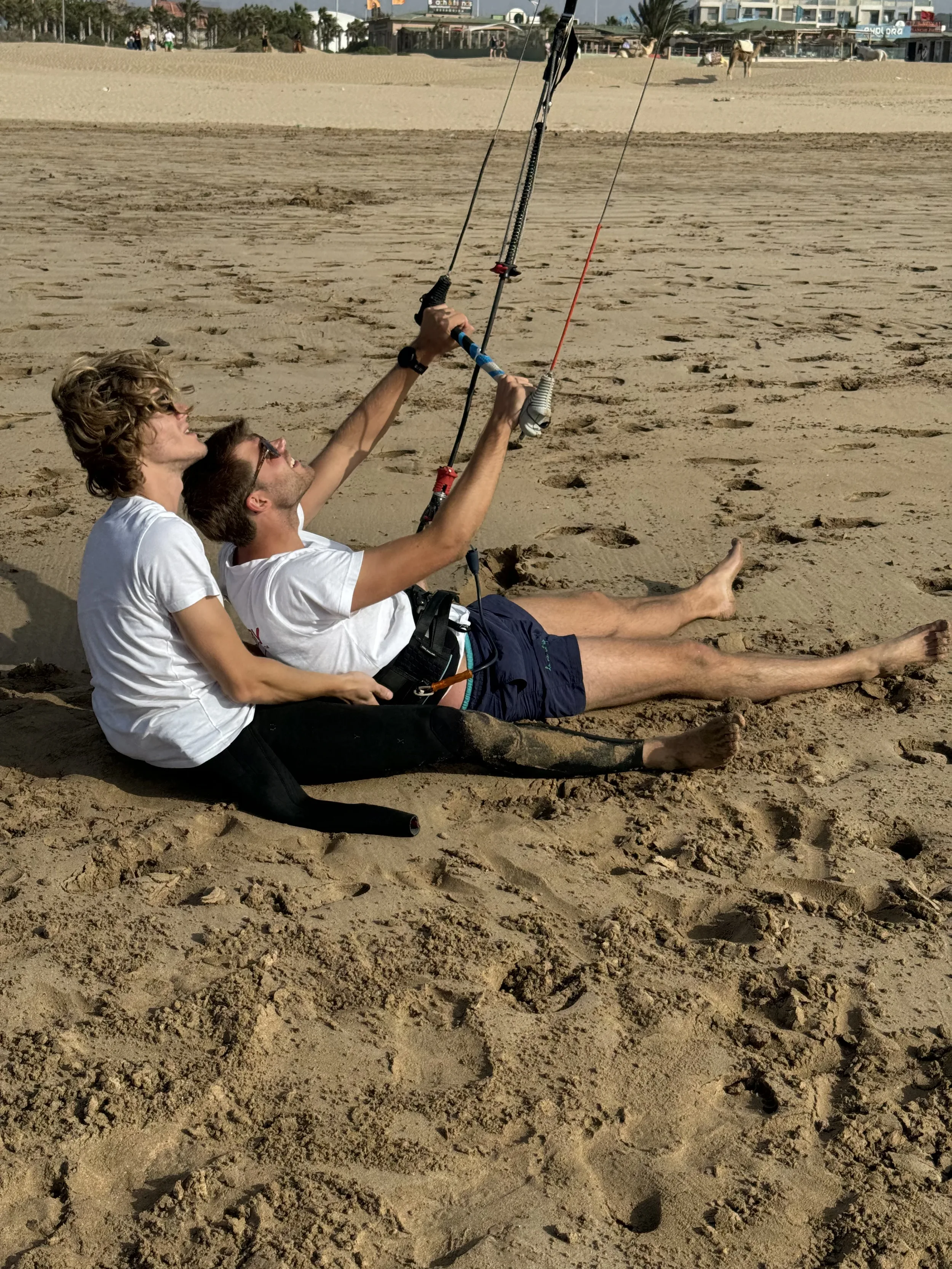 Cours de kitesurf sur la plage, deux personnes assises s'exerçant au maniement de la barre