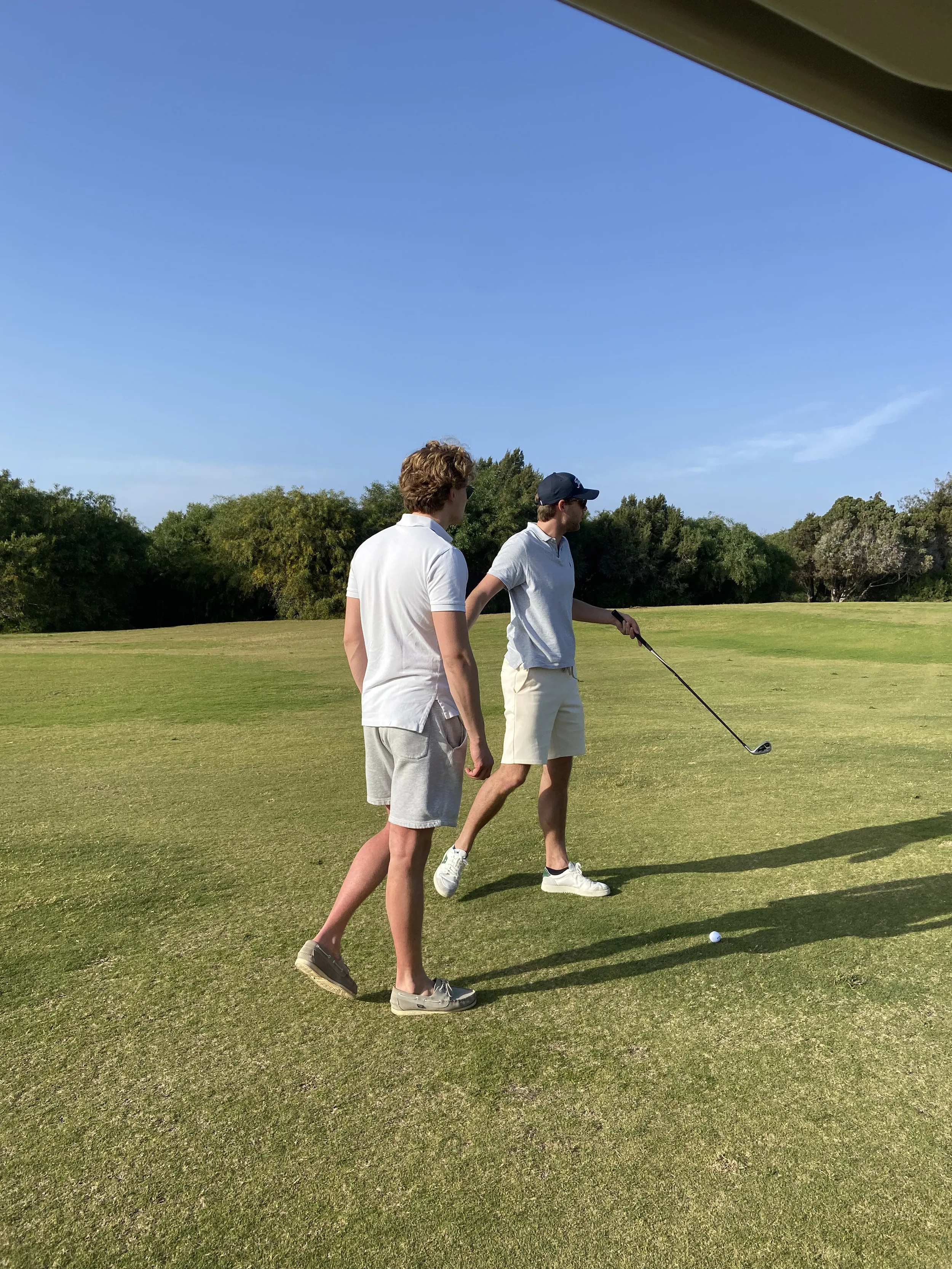 Two golfers walking on the fairway of a golf course under a blue sky near Essaouira