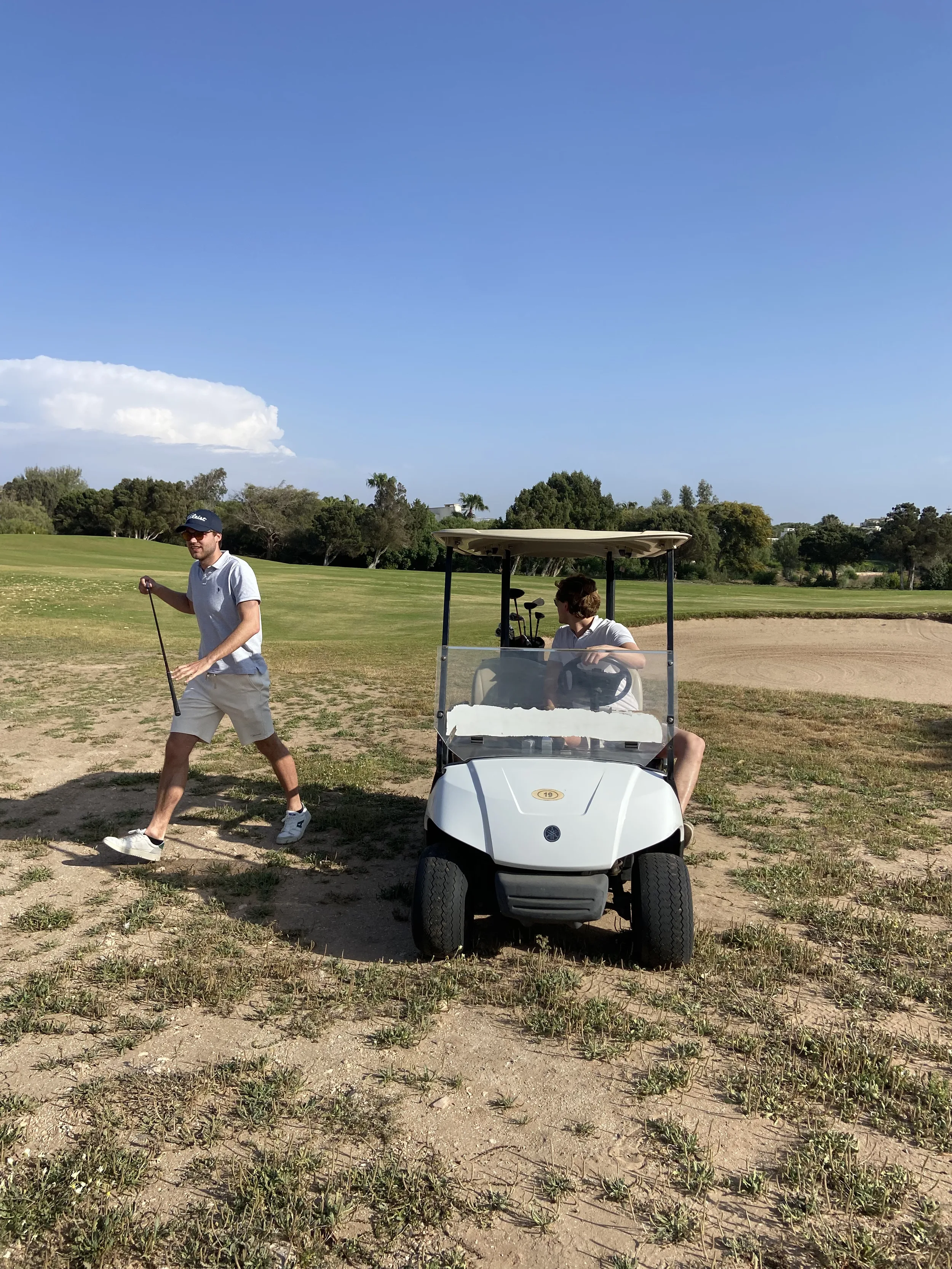 Deux golfeurs avec voiturette sur un parcours de golf verdoyant près d'Essaouira