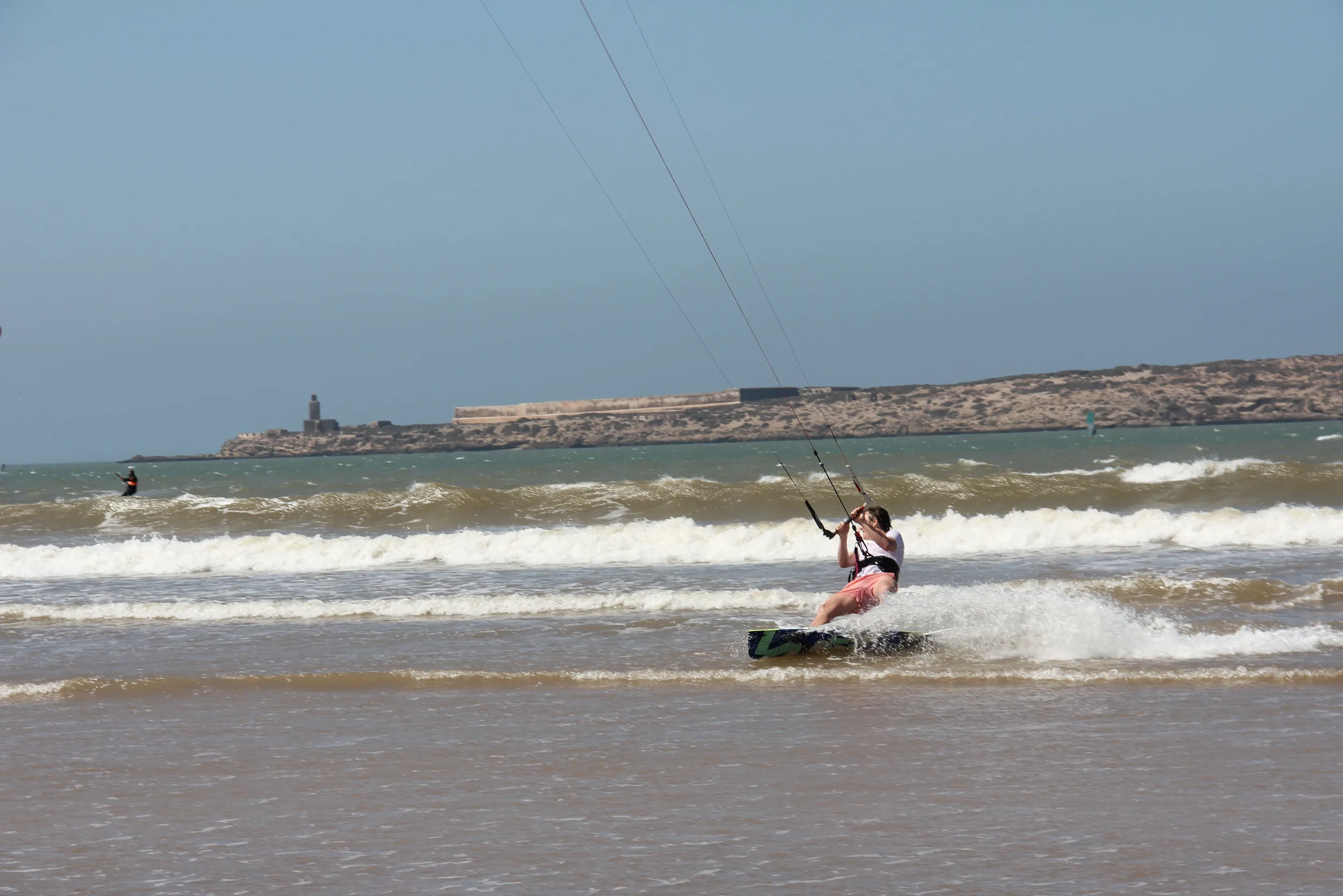 Kitesurfeur naviguant vers le rivage dans l'écume, fort des îles d'Essaouira en arrière-plan