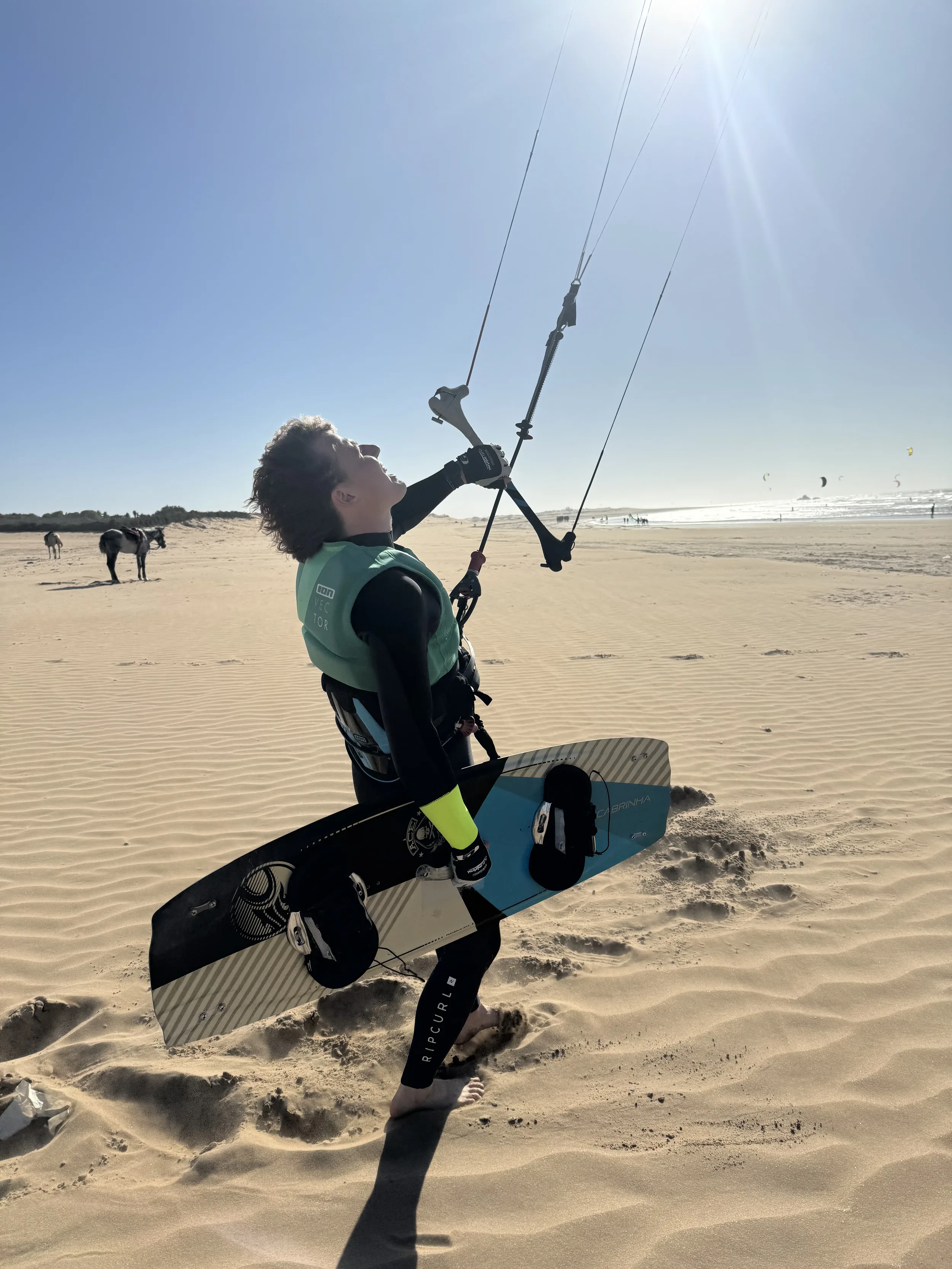 Kitesurfeur maniant sa barre et tenant sa planche sur une plage de sable près d'Essaouira