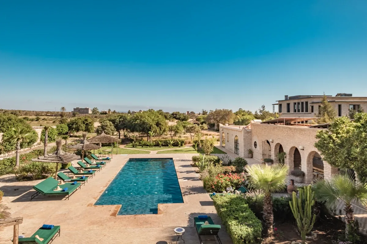 Vue d'ensemble de la piscine, du jardin paysager et de la villa sous un grand ciel bleu