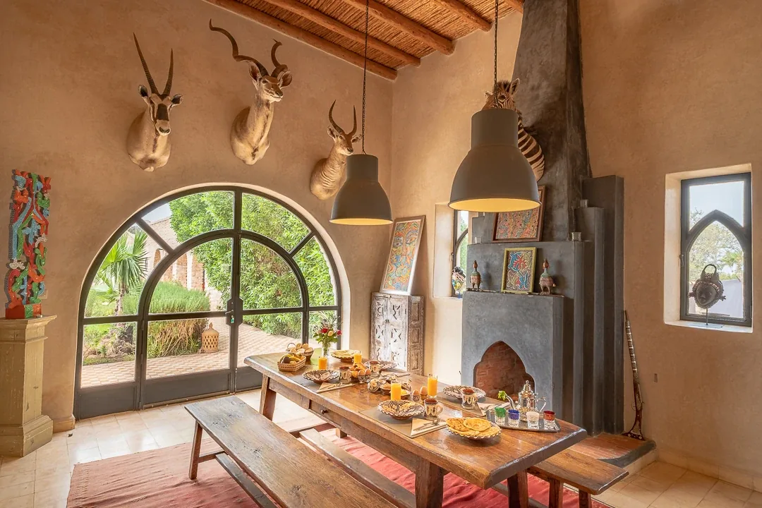 Salle à manger lumineuse avec hautes arches, grandes suspensions et table dressée pour le repas