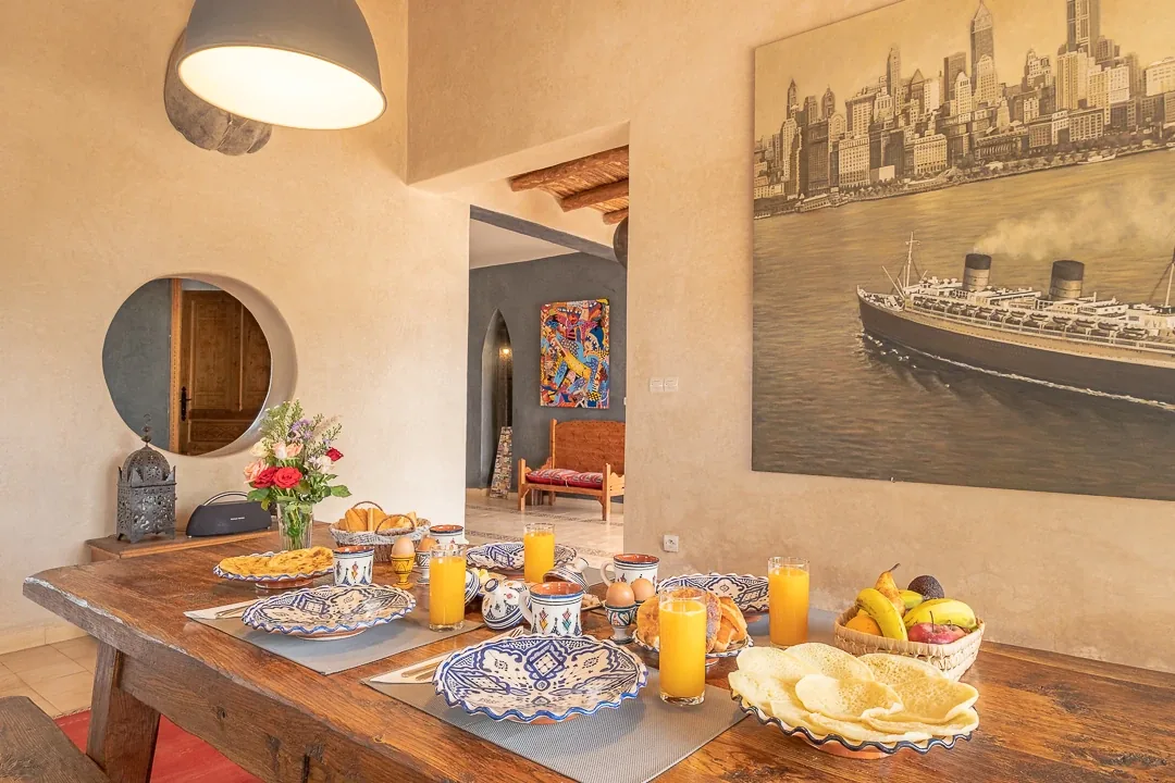 Breakfast table with blue ceramic dishes, round mirror and ship painting on the wall