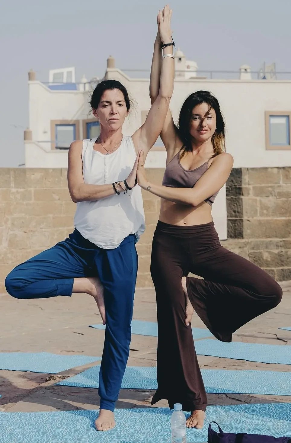 Deux femmes en posture de l'arbre lors d'un cours de yoga sur un toit-terrasse